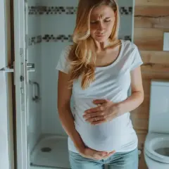 Kobieta w ciąży, w 3 trymestrze, trzyma się za brzuch z powodu bólu brzucha jak na okres.