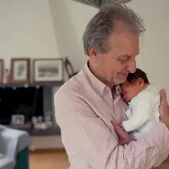 Dziadek tuli śpiące niemowlę, które mimo senności nie chce zasnąć.