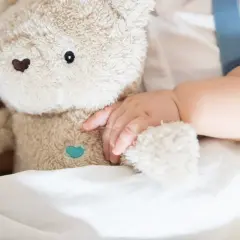 Niemowlę tuli pluszowego misia, przygotowując się do turbo drzemki. Miękkie futerko i delikatna rączka tworzą obraz spokoju.
