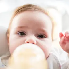 Urocze niemowlę pije mleko z butelki. Ważne jest, jaka temperatura mleka dla noworodka, by było bezpieczne i smaczne.