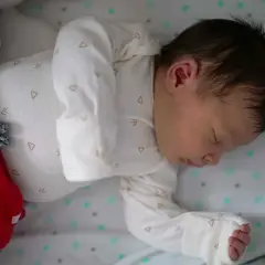 Śpiące niemowlę w czerwonych spodenkach i białym body. Ile powinno spac 9 miesieczne niemowle? To pytanie nurtuje wielu rodziców.