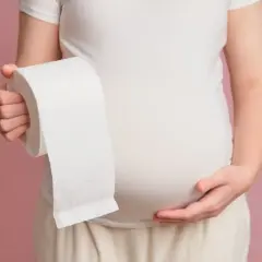 Kobieta w ciąży trzyma rolkę papieru toaletowego, sugerując problem z biegunką w ciąży.