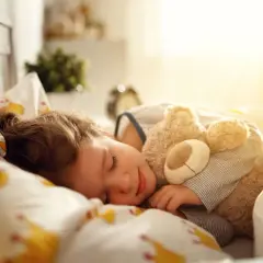 Słodki sen dziecka z misiem. Idealna drzemka powinna trwać tyle, by dziecko obudziło się wypoczęte.