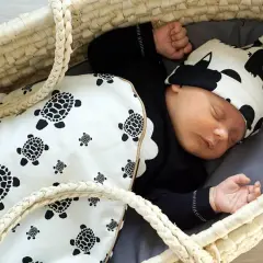 Śpiący noworodek w koszu, przykryty kocykiem w żółwie. Idealne rozwiązanie, czym przykrywać niemowlaka do snu.