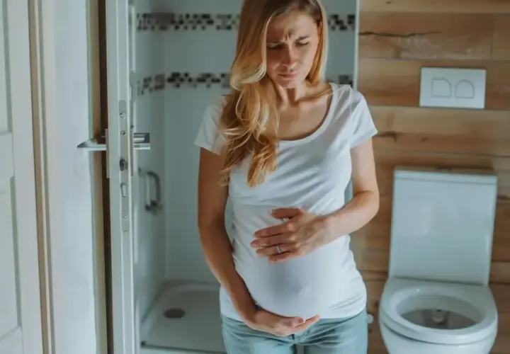 Kobieta w ciąży, w 3 trymestrze, trzyma się za brzuch z powodu bólu brzucha jak na okres.