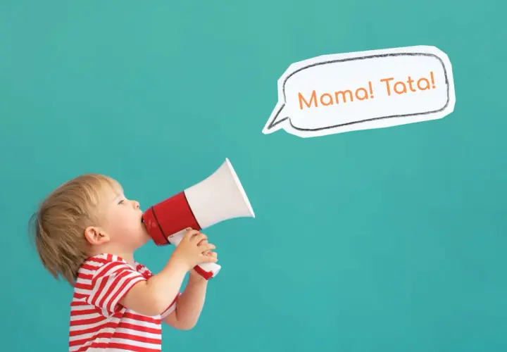 Mały chłopiec w czerwono-białej koszulce trzyma megafon, z którego wydobywa się "Mama! Tata!". To uroczy moment, kiedy dziecko zaczyna gaworzyć.