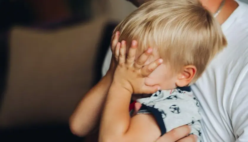 2-letnie dziecko budzi się w nocy z płaczem, ukrywając twarz w dłoniach. Tata tuli go, próbując uspokoić.