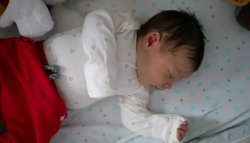 Śpiące niemowlę w czerwonych spodenkach i białym body. Ile powinno spac 9 miesieczne niemowle? To pytanie nurtuje wielu rodziców.