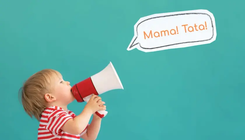 Mały chłopiec w czerwono-białej koszulce trzyma megafon, z którego wydobywa się "Mama! Tata!". To uroczy moment, kiedy dziecko zaczyna gaworzyć.