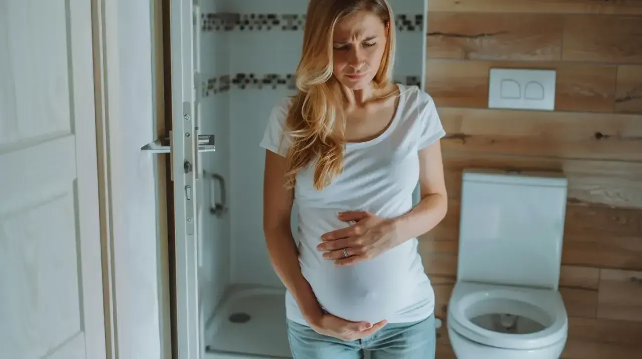 Kobieta w ciąży, w 3 trymestrze, trzyma się za brzuch z powodu bólu brzucha jak na okres.
