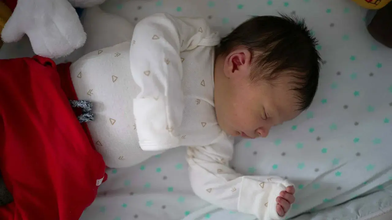 Śpiące niemowlę w czerwonych spodenkach i białym body. Ile powinno spac 9 miesieczne niemowle? To pytanie nurtuje wielu rodziców.