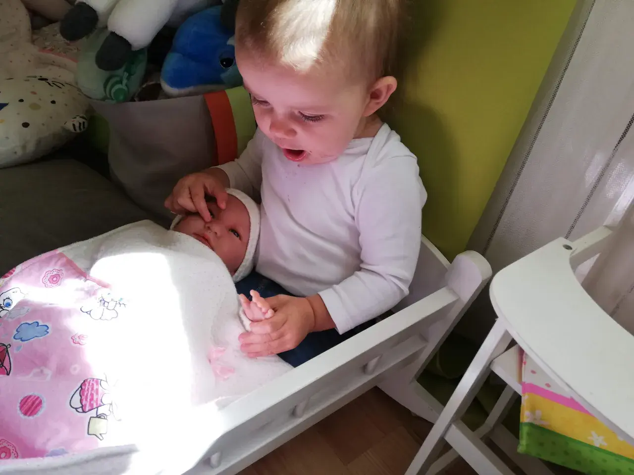 Starszy brat opiekuje się młodszym, który leży w łóżeczku. To piękny przykład skoku rozwojowego 18 miesiąc, gdy dzieci uczą się empatii.