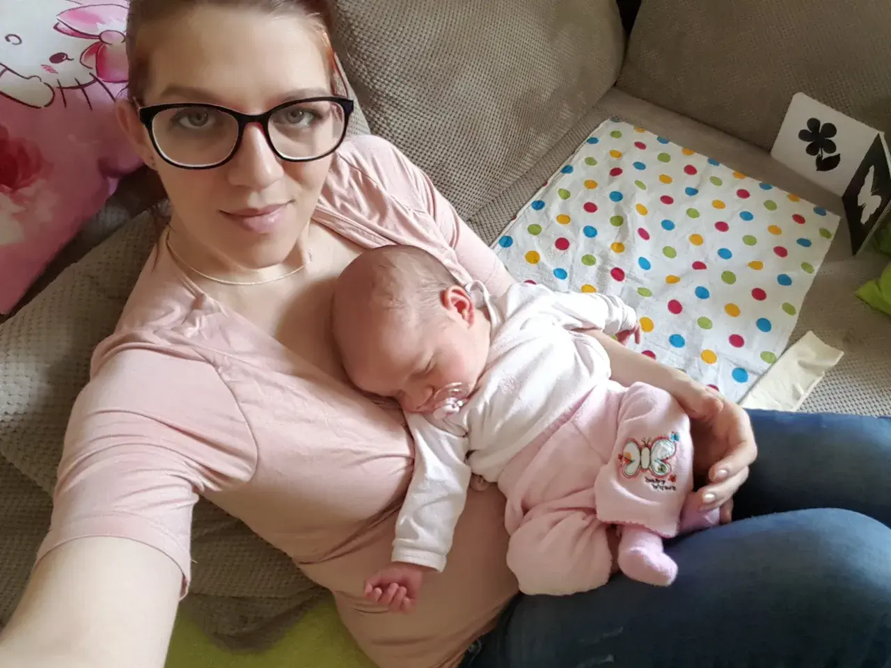 Mama z dzieckiem na rękach. Maluch śpi, jak widzi dziecko w 3 miesiącu, otoczony troską.