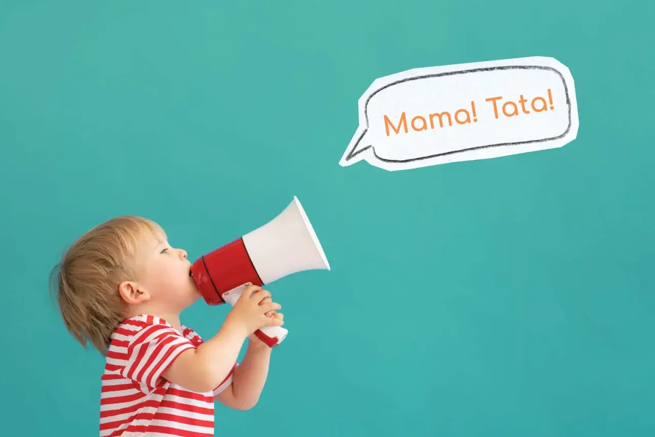Mały chłopiec w czerwono-białej koszulce trzyma megafon, z którego wydobywa się "Mama! Tata!". To uroczy moment, kiedy dziecko zaczyna gaworzyć.