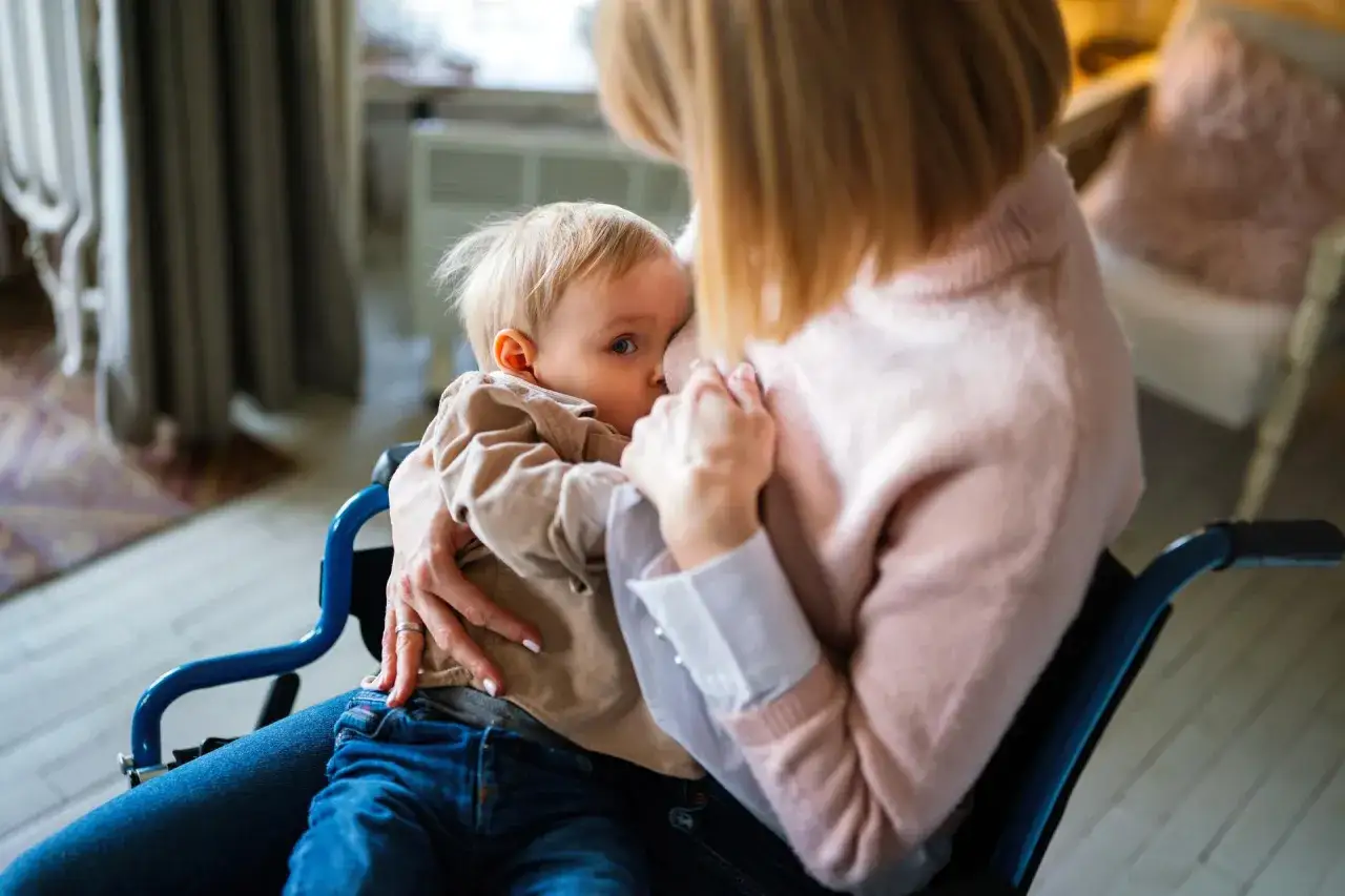 Mama w w&oacute;zku inwalidzkim karmi piersią dziecko. Wkr&oacute;tce przyjdzie czas, jak odstawić dziecko od piersi.