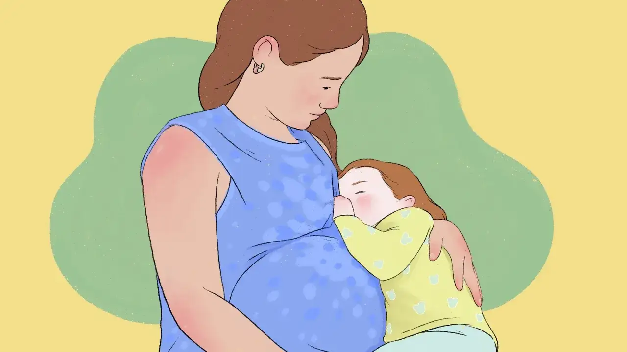 Ciąża a karmienie piersią: młoda mama karmi starsze dziecko, mimo że sama jest w ciąży.