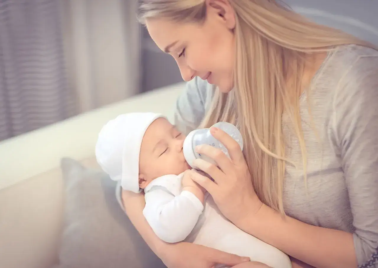 Mama z czułością karmi butelką swoje dziecko. To piękny przykład karmienia mieszanego, gdzie miłość i troska są najważniejsze.